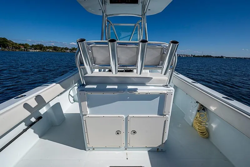 Slide: The Image of 2000 Regulator 26 Forward Seating boat on calm water, featuring rod holders and storage compartments. - 9