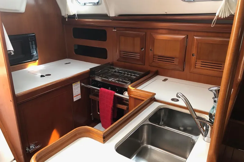 Slide: The Image of 2003 Beneteau 361 yacht kitchen with stove, sink, and wooden cabinetry. - 6