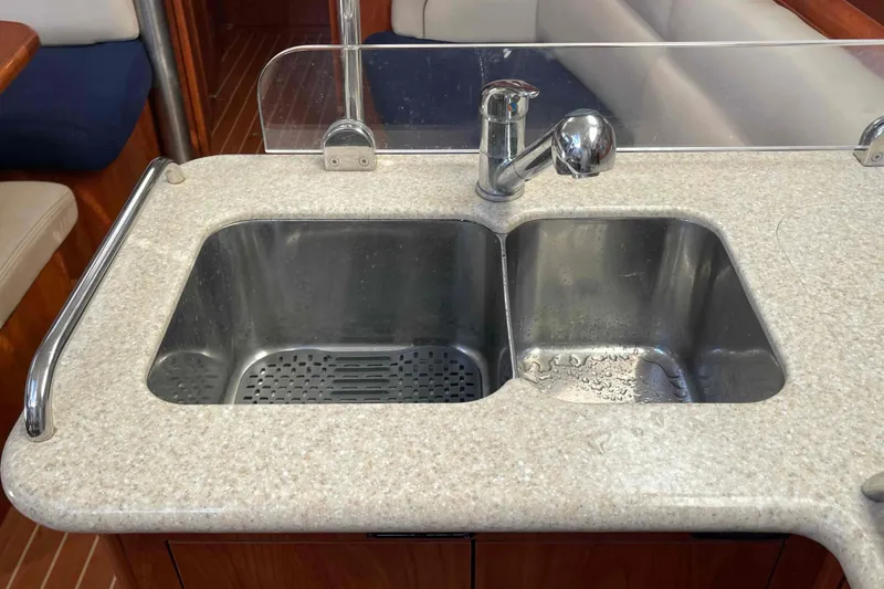 Slide: The Image of 2010 Hunter 45 Center Cockpit kitchen with dual sinks, stove, and wooden cabinetry. - 5