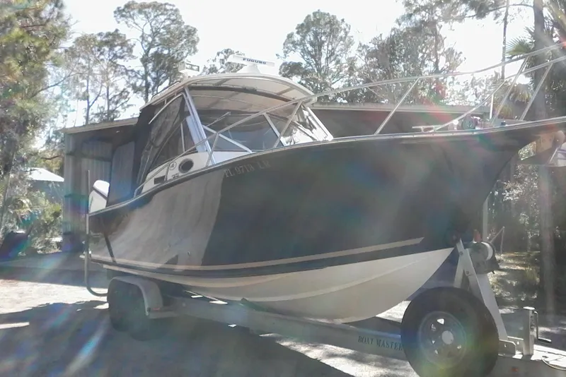 Slide: The Image of 2002 Albemarle 265 Express Fisherman boat on trailer, parked near a house with trees. - 4