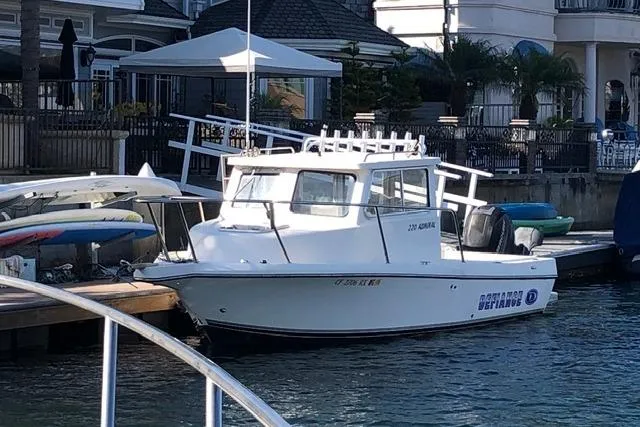 Slide: The Image of 2015 Defiance 220 Admiral EX boat docked at a marina with waterfront homes. - 2