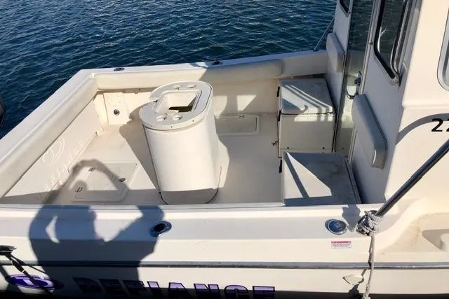 Slide: The Image of 2015 Defiance 220 Admiral EX boat deck with seating and storage, docked on calm water. - 5