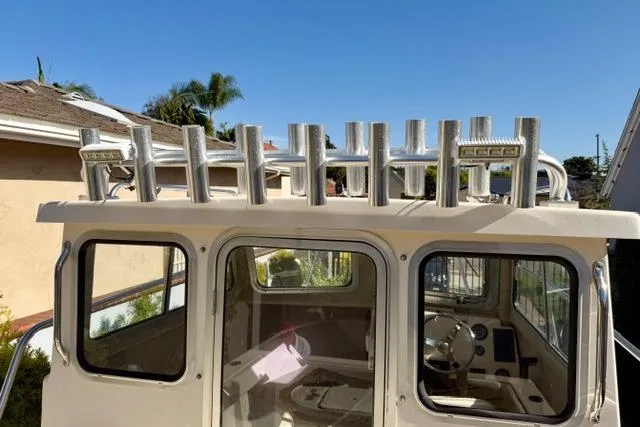 Slide: The Image of 2015 Defiance 220 Admiral EX boat with rod holders and cabin, under clear blue sky. - 7