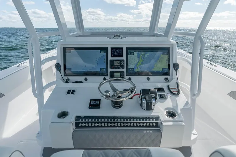 Slide: The Image of Manufacturer Provided Image: 2026 Invincible 40 Catamaran helm with dual navigation screens, steering wheel, and ocean view. - 3