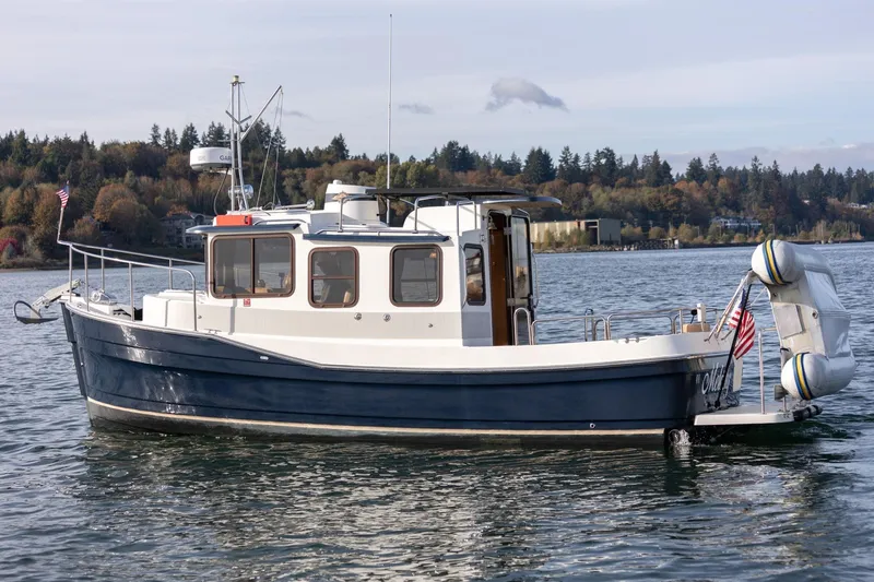 The Image of 2012 Ranger Tugs R-25 SC boat on calm water with scenic forest backdrop. - 0