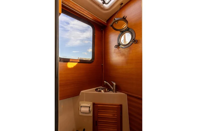 Slide: The Image of 2012 Ranger Tugs R-25 SC interior bathroom with wooden walls and porthole window. - 11