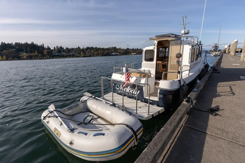 Slide: The Image of 2012 Ranger Tugs R-25 SC docked with inflatable boat, scenic waterfront view. - 4