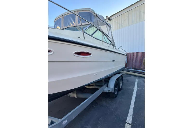 Slide: The Image of 1985 Sea Ray 255 SVR boat on trailer, parked outdoors near a building. - 11