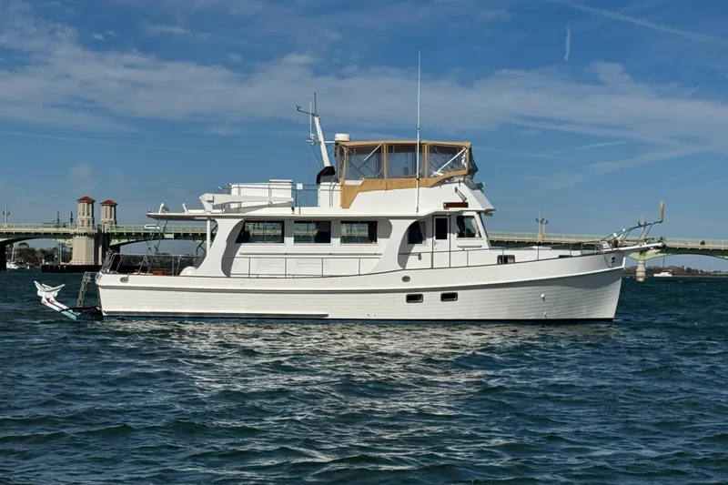 The Image of Grand Banks 52 Europa 2000 yacht on water near a bridge under blue sky. - 0