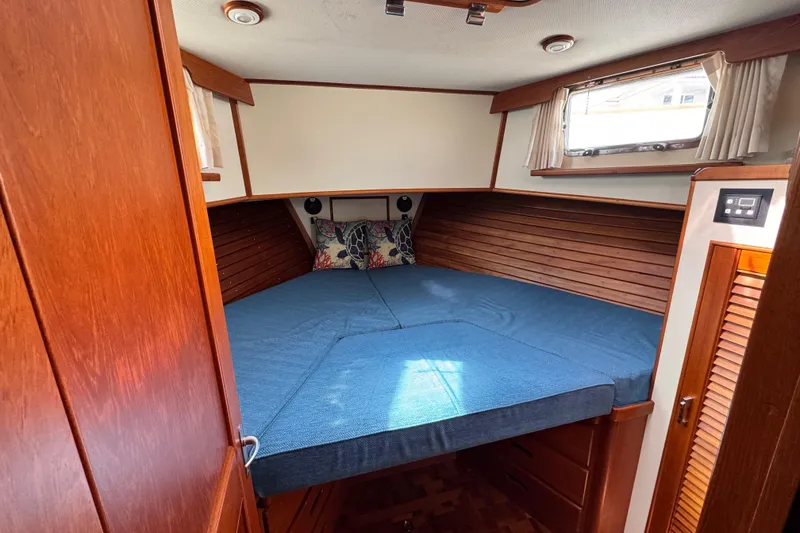 Slide: The Image of Cozy cabin interior of 2000 Grand Banks 52 Europa yacht with wooden accents and blue bedding. - 23