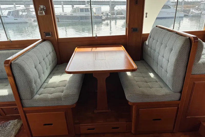 Slide: The Image of Interior of 2000 Grand Banks 52 Europa yacht with cushioned dining area and wooden table. - 5
