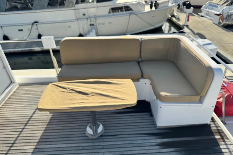 Slide: The Image of Outdoor seating area on a 2000 Grand Banks 52 Europa yacht, featuring cushioned benches and a covered table. - 68