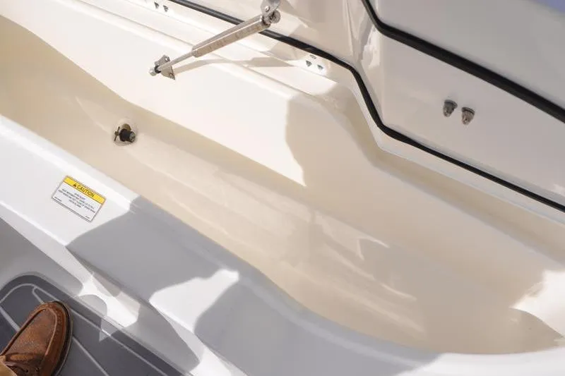 Slide: The Image of 2016 Boston Whaler 270 Dauntless interior detail with storage compartment and safety label. - 32