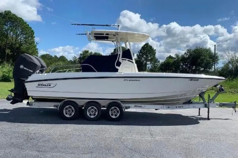 Slide: The Image of 2016 Boston Whaler 270 Dauntless boat on trailer, parked outdoors under a cloudy sky. - 40