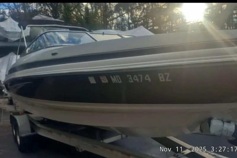 Slide: The Image of 2008 Larson LXi 268 boat on trailer, sunlight filtering through trees. - 2