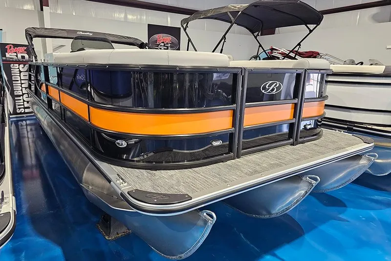Slide: The Image of 2026 Bentley Pontoons Legacy 243 Swingback with orange and black design in showroom. - 3