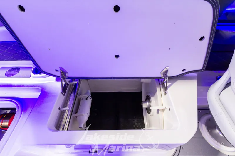 Slide: The Image of Open storage compartment in 2026 Chaparral SSX 6 boat with blue ambient lighting. - 7