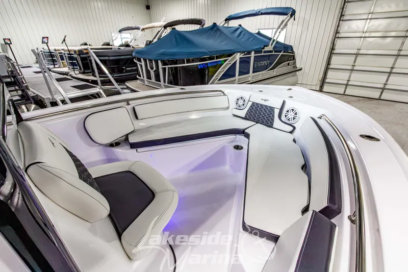 Slide: The Image of 2026 Tidewater 210 CC Adventure boat interior with cushioned seating and speakers in showroom. - 33