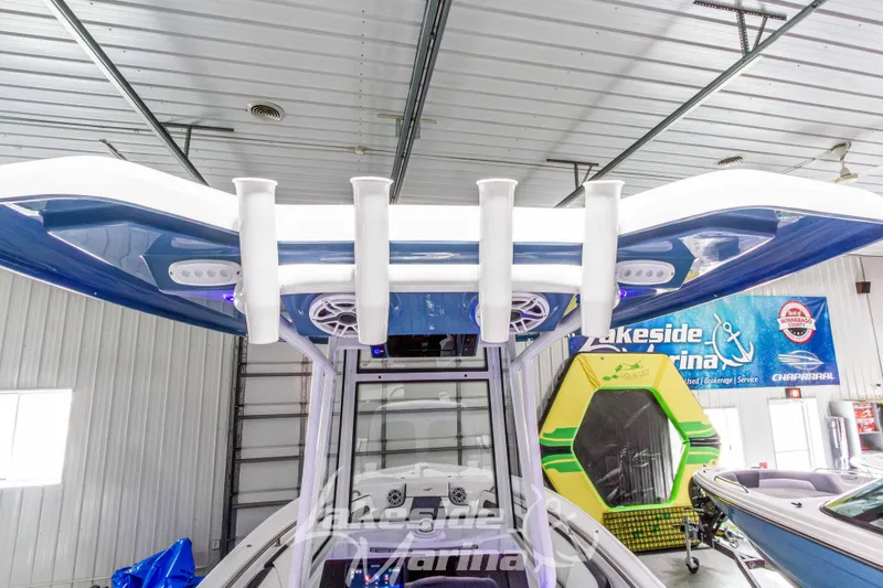 Slide: The Image of 2026 Tidewater 220 LXF boat interior with rod holders and speakers in a marina showroom. - 25