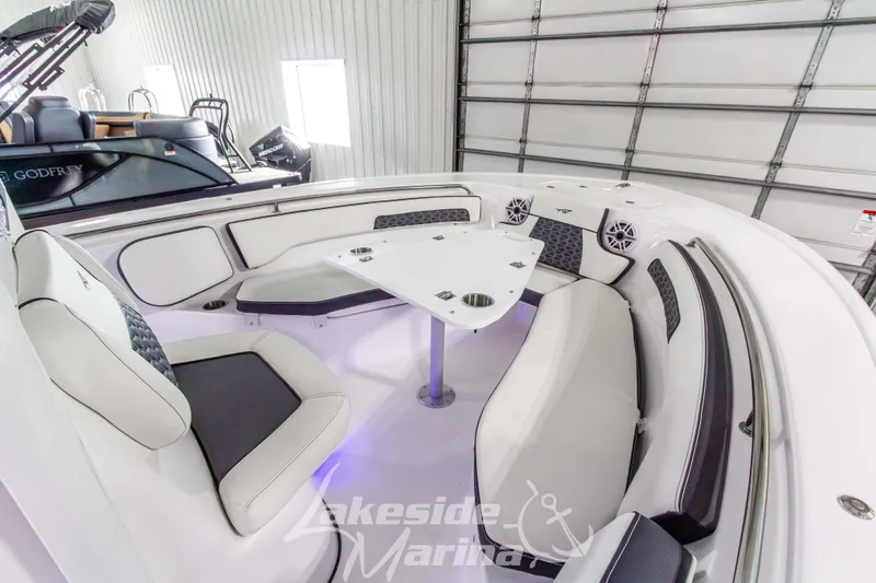 Slide: The Image of 2026 Tidewater 220 LXF boat interior with cushioned seating and table in a marina. - 42