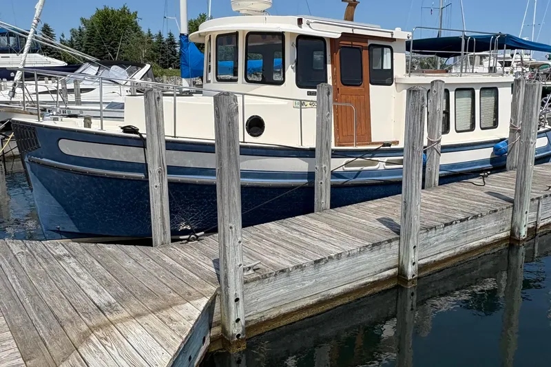 The Image of 1999 Nordic Tug 32 docked at a marina, featuring a classic blue and white design. - 0