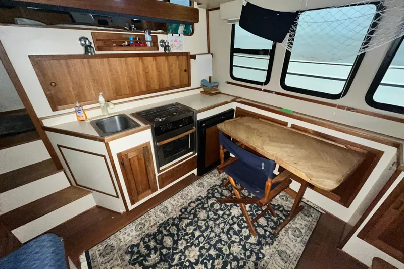 Slide: The Image of Interior of a 1999 Nordic Tug 32, featuring a compact kitchen and dining area. - 12