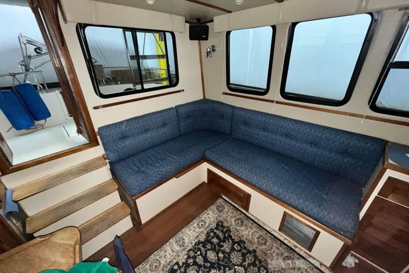 Slide: The Image of Interior of 1999 Nordic Tug 32 with blue L-shaped seating and wooden accents. - 13