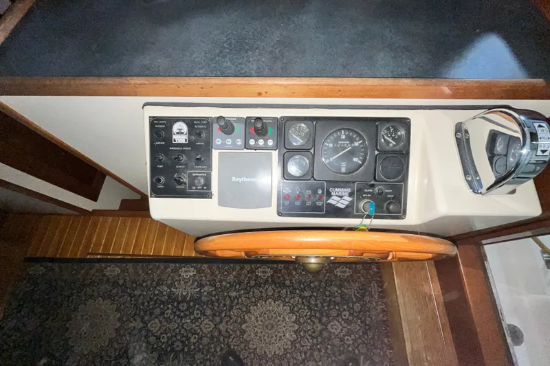 Slide: The Image of 1999 Nordic Tug 32 helm with control panel, gauges, and wooden steering wheel. - 15