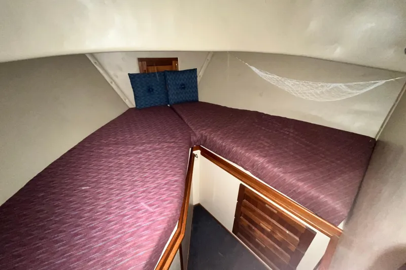 Slide: The Image of 1999 Nordic Tug 32 interior cabin with purple bedding and blue cushions. - 19