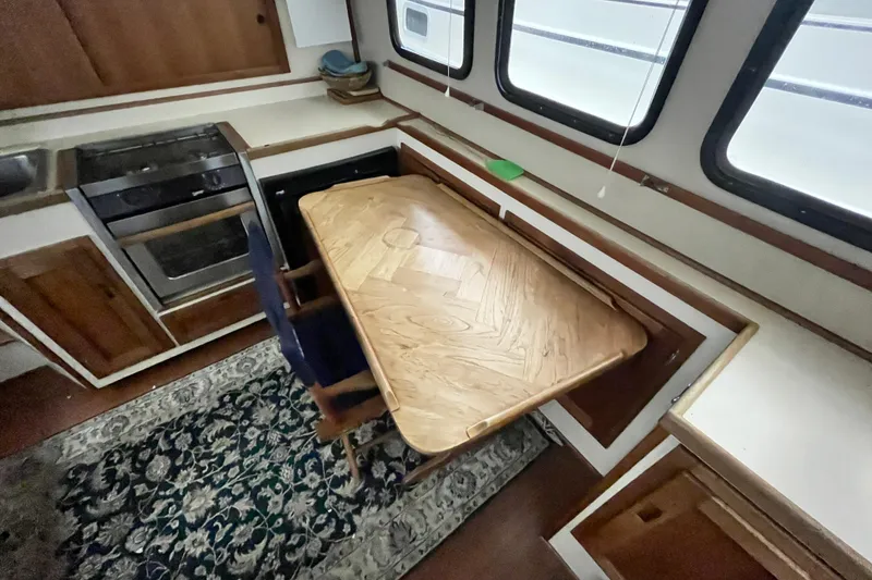 Slide: The Image of Interior of 1999 Nordic Tug 32 with wooden table, chairs, and kitchen area. - 9