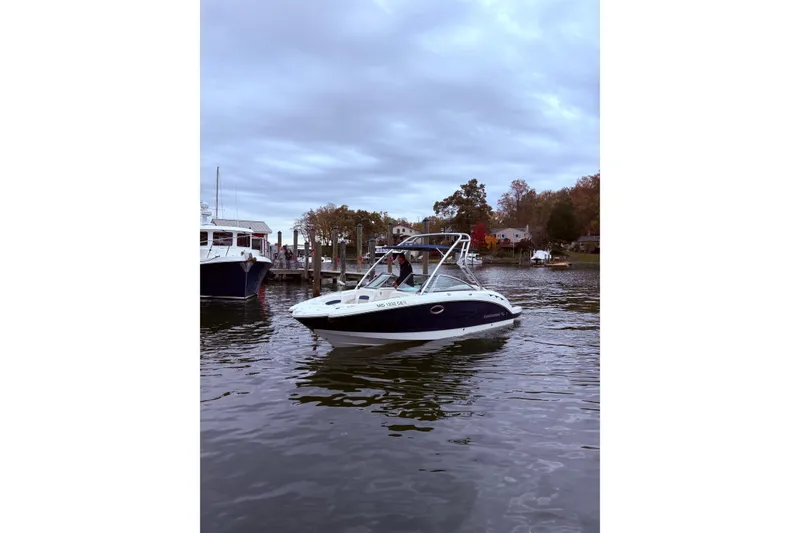 The Image of 2009 Chaparral Sunesta 244 boat docked on a calm lake under cloudy skies. - 1