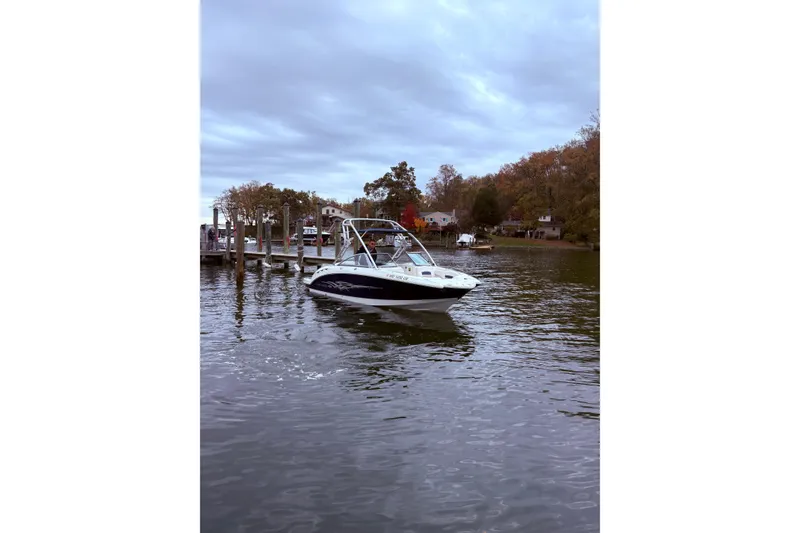 Slide: The Image of 2009 Chaparral Sunesta 244 boat on a calm lake near a dock, surrounded by autumn trees. - 4