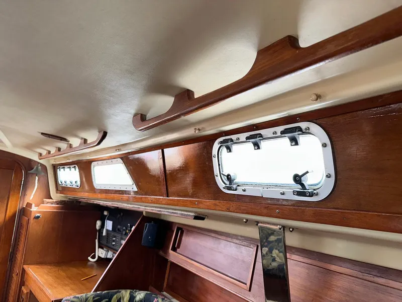 Slide: The Image of Interior of a 1987 Pearson 36-2 sailboat, featuring wooden cabinetry and portholes. - 5