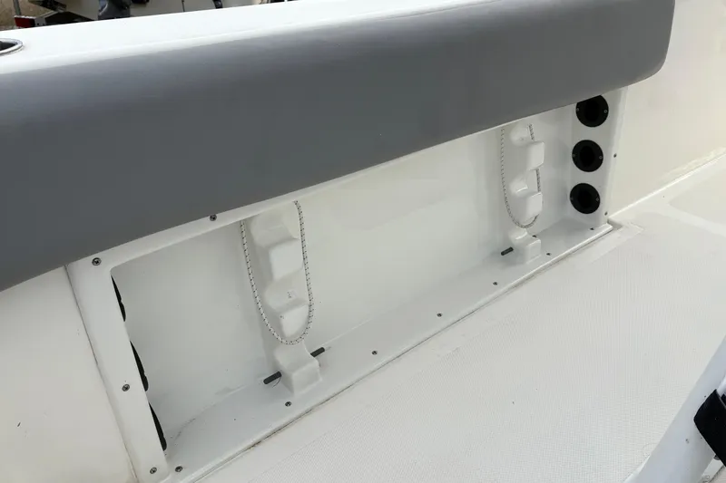 Slide: The Image of 2022 NauticStar 2302 Legacy boat interior detail with storage compartment and rod holders. - 16