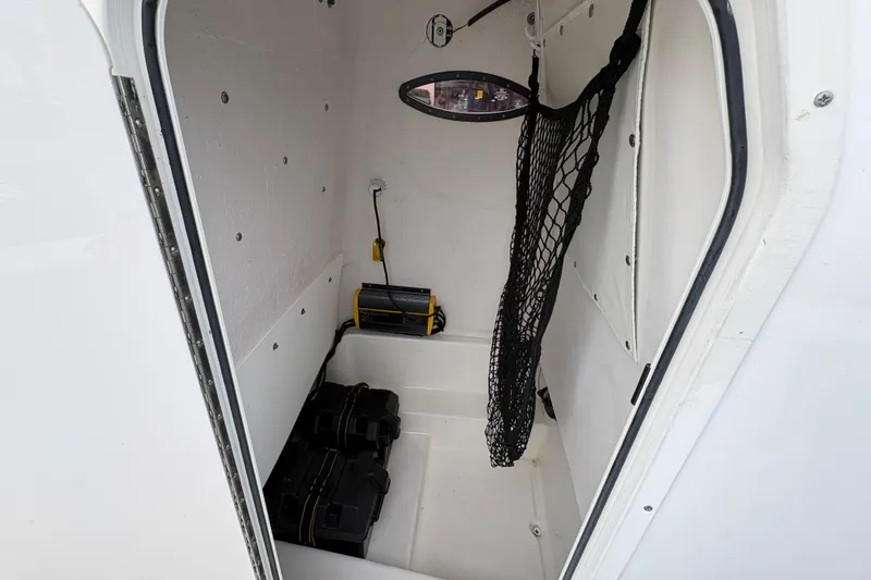 Slide: The Image of 2022 NauticStar 2302 Legacy boat storage compartment with netting and equipment. - 27