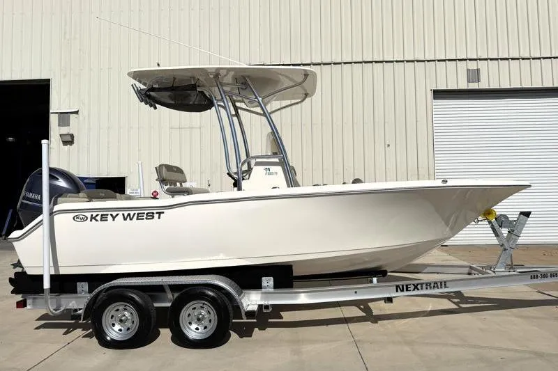 The Image of 2023 Key West 203 FS boat on trailer, parked outside industrial building. - 0