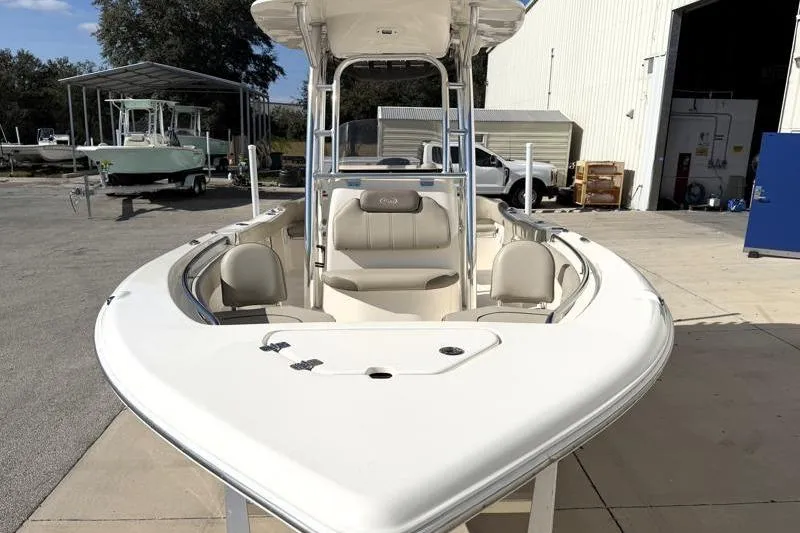 Slide: The Image of 2023 Key West 203 FS boat, white exterior, parked outdoors near a warehouse. - 6