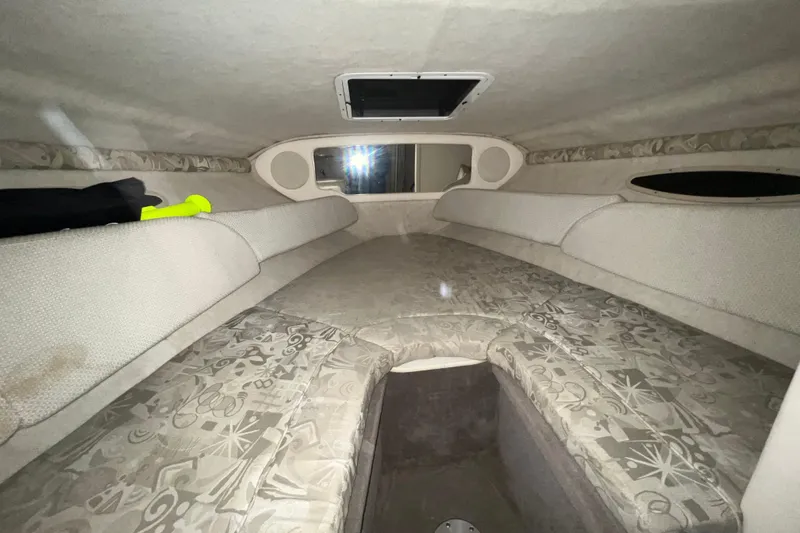 Slide: The Image of 2003 Sea Ray 225 Weekender cabin interior with cushioned seating and overhead hatch. - 14