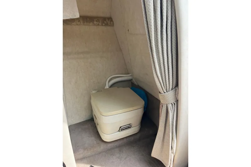 Slide: The Image of 2003 Sea Ray 225 Weekender cabin with portable toilet and privacy curtain. - 17