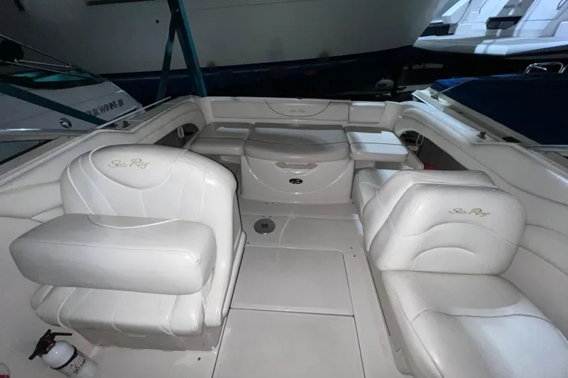 Slide: The Image of 2003 Sea Ray 225 Weekender boat interior with white leather seating and storage compartments. - 3