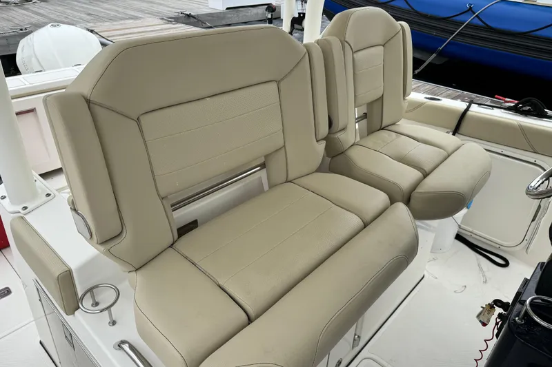 Slide: The Image of 2018 Pursuit S 328 Sport boat with beige cushioned seating on deck. - 11