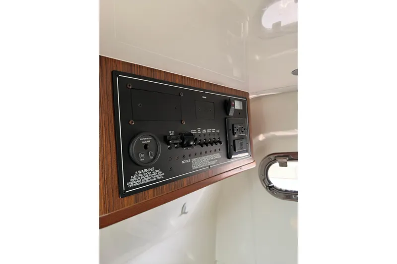 Slide: The Image of Control panel inside 2018 Pursuit S 328 Sport boat, featuring switches and warning labels. - 16