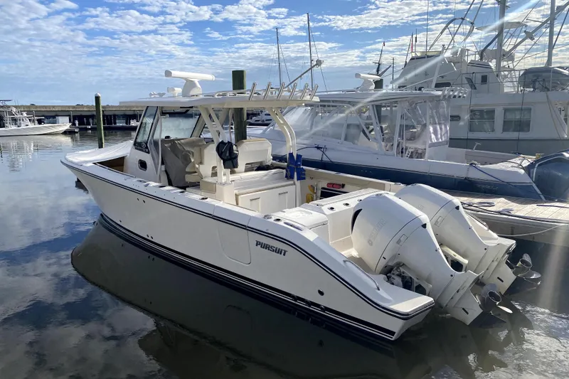 Slide: The Image of 2018 Pursuit S 328 Sport boat docked in a marina under a blue sky. - 3
