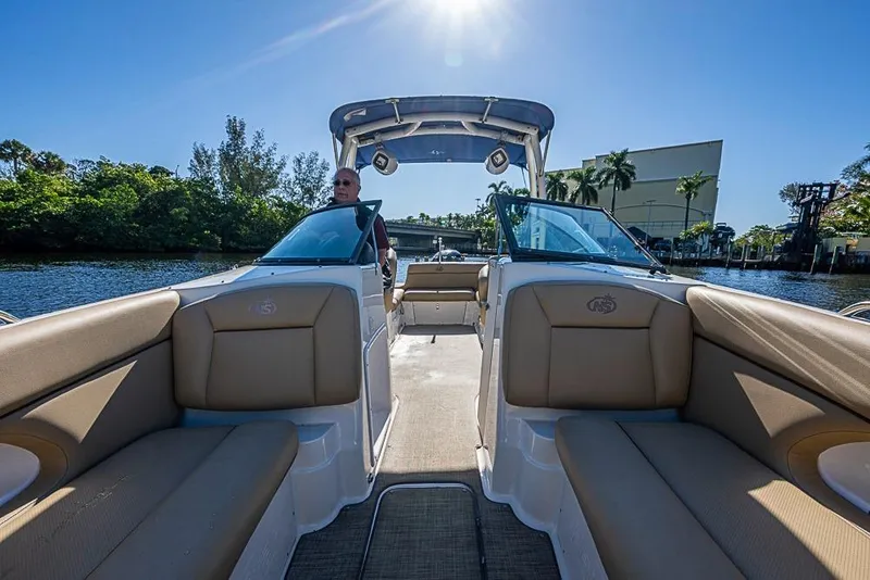 Slide: The Image of 2019 NauticStar 243DC Sport Deck boat interior with tan seating, cruising on a sunny day. - 14