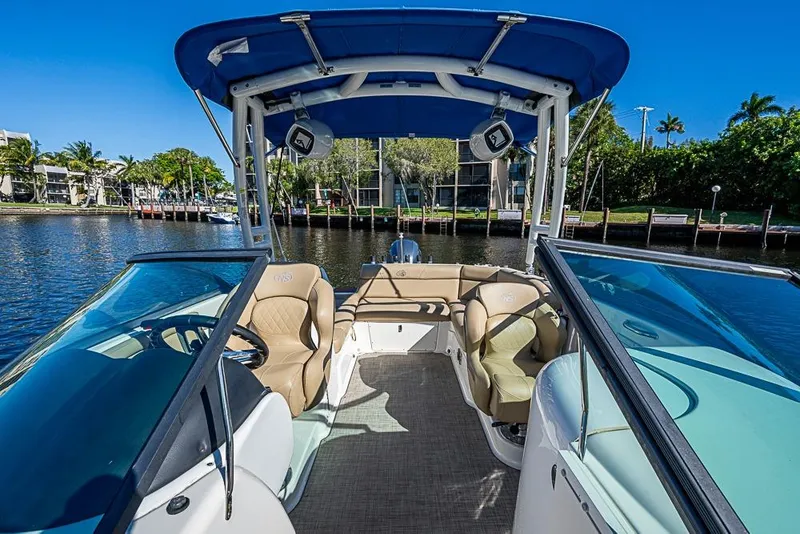 Slide: The Image of 2019 NauticStar 243DC Sport Deck boat interior with blue canopy, docked by waterfront homes. - 16