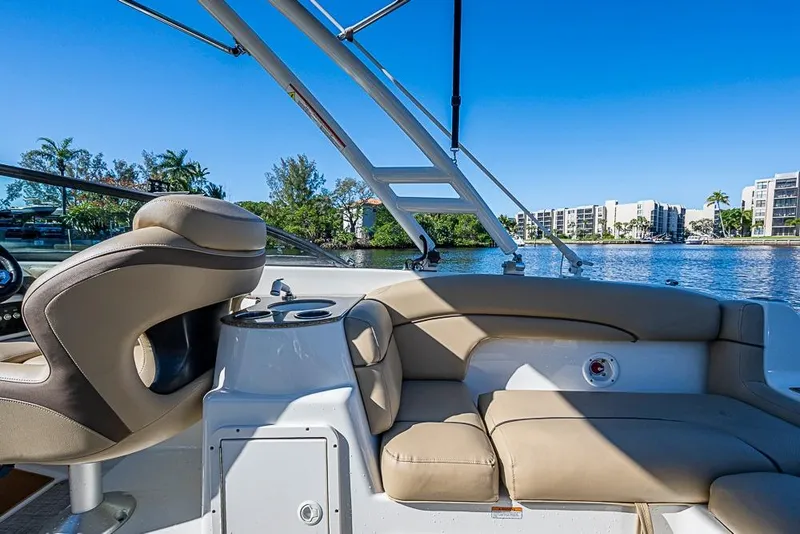 Slide: The Image of 2019 NauticStar 243DC Sport Deck boat interior with seating, cup holders, and scenic waterfront view. - 23
