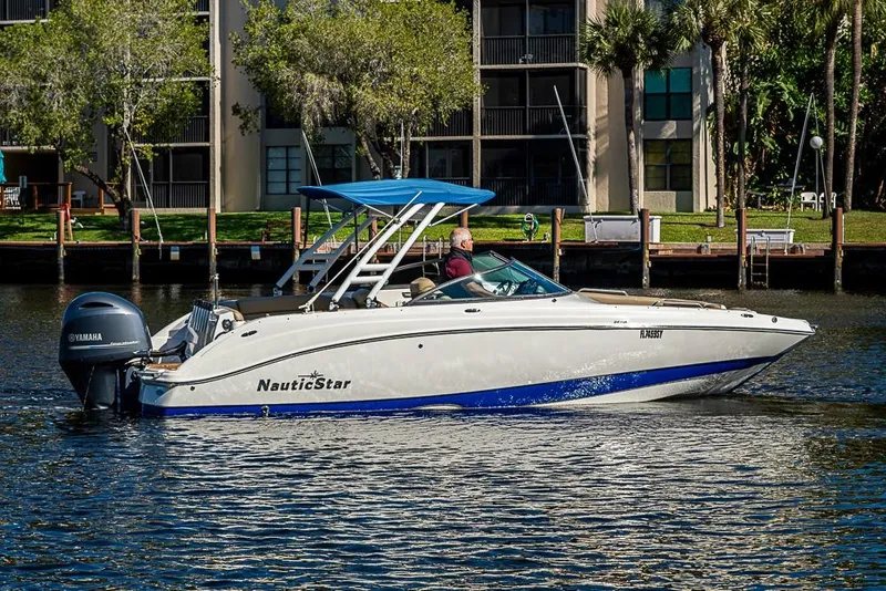 Slide: The Image of 2019 NauticStar 243DC Sport Deck boat cruising on a sunny day with a blue canopy. - 26