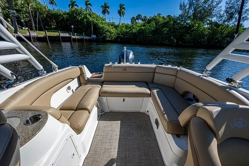 Slide: The Image of 2019 NauticStar 243DC Sport Deck boat interior with tan seating, on a sunny day. - 4