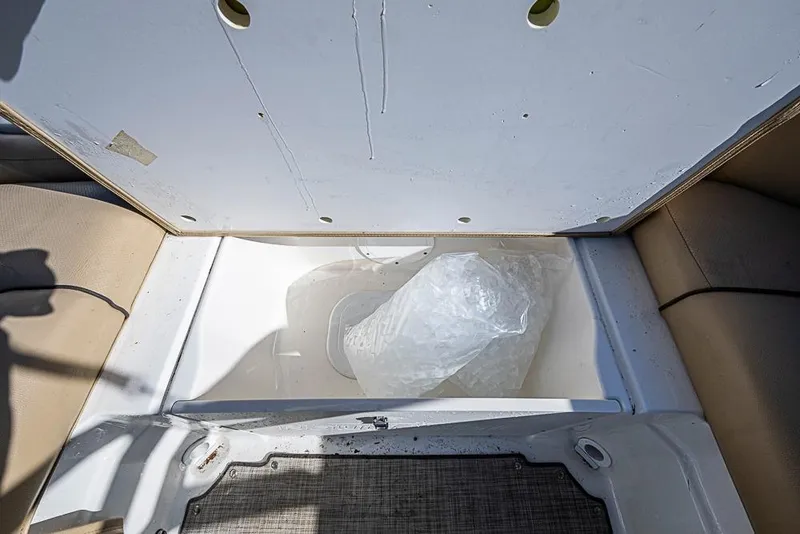 Slide: The Image of 2019 NauticStar 243DC Sport Deck storage compartment with ice bag inside. - 7