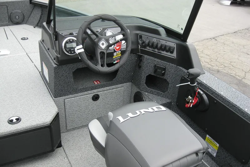 Slide: The Image of 2025 Lund 1875 Impact XS Sport boat interior with steering wheel and control panel. - 12